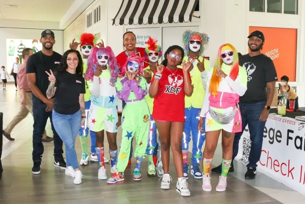 Xtreme Dreams Foundation team and youth in bright costumes at a community college fair event