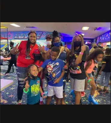 Group posing at a bowling alley, smiling and holding up peace signs.