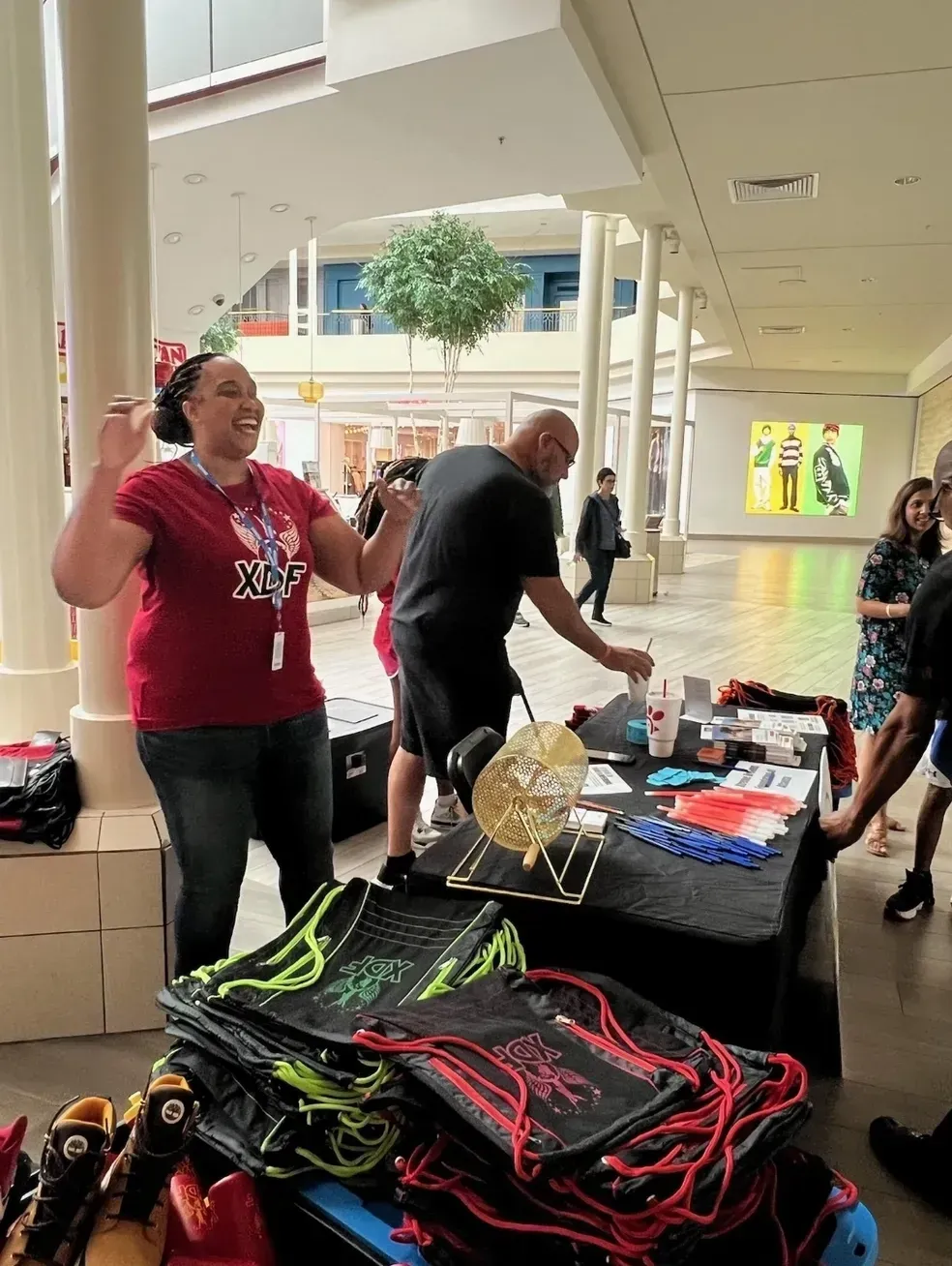 People at a community event displaying athletic jump ropes and gear at a table inside a mall corridor.