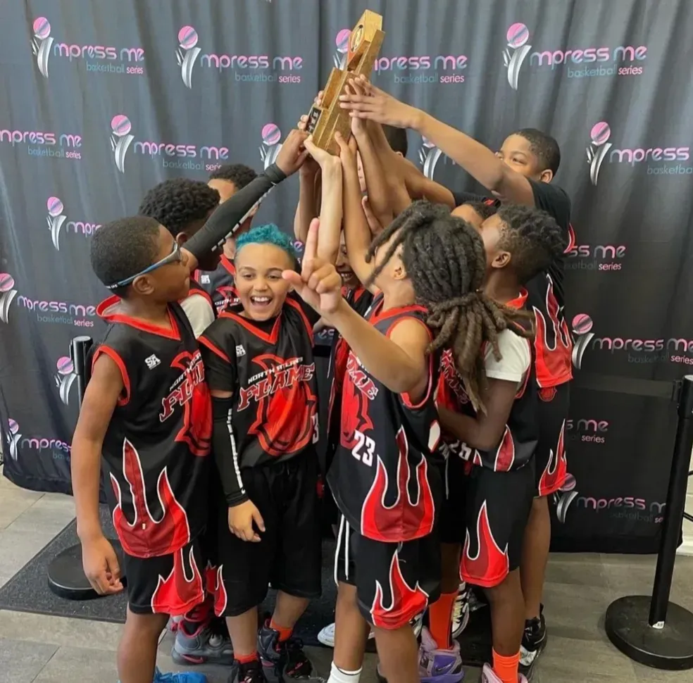 Young basketball players celebrating together with a trophy
