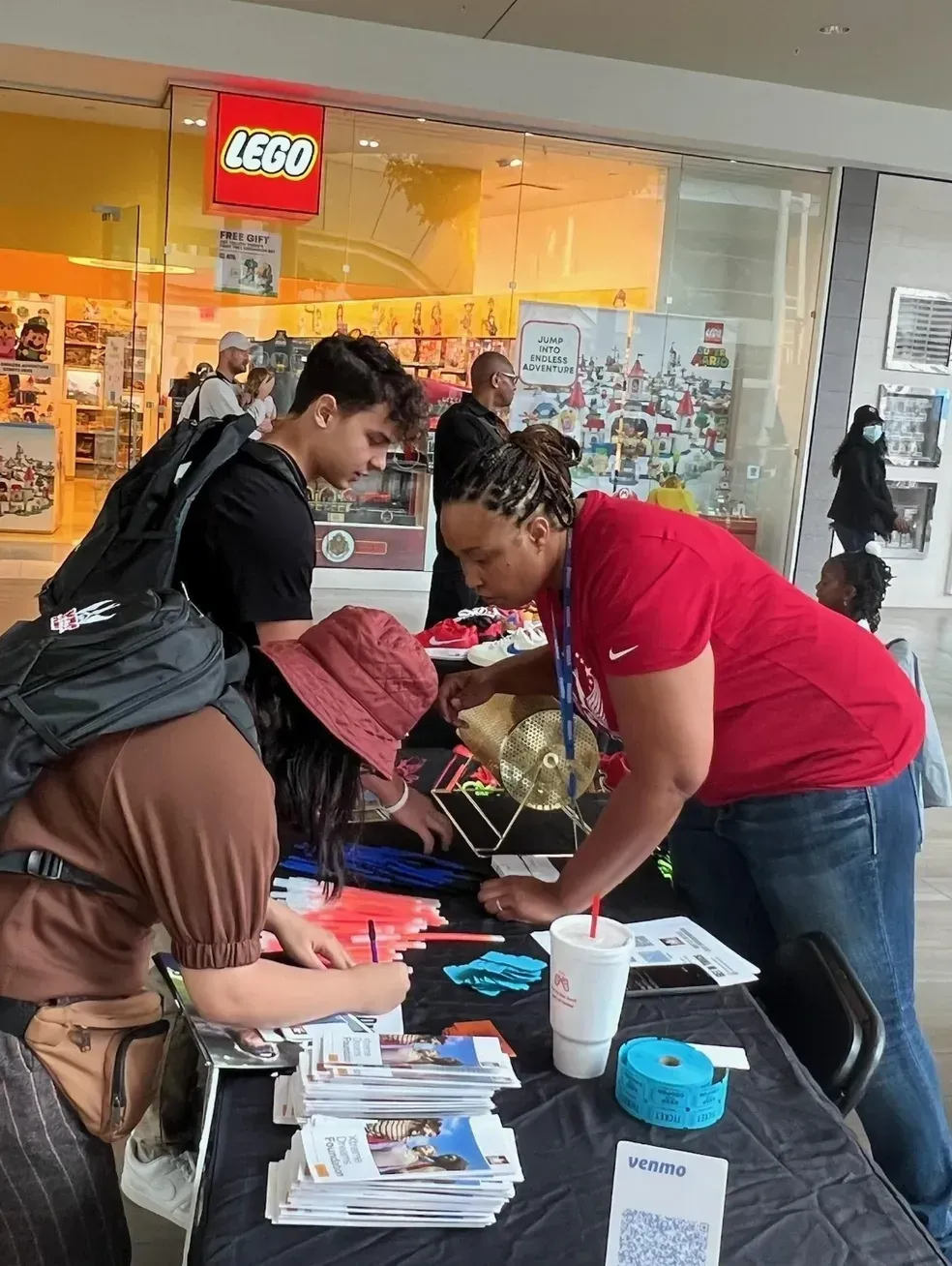 Xtreme Dreams team member welcoming young people at an event table