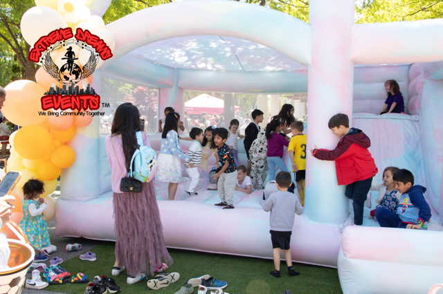 Children playing in a white inflatable bounce house at an outdoor event